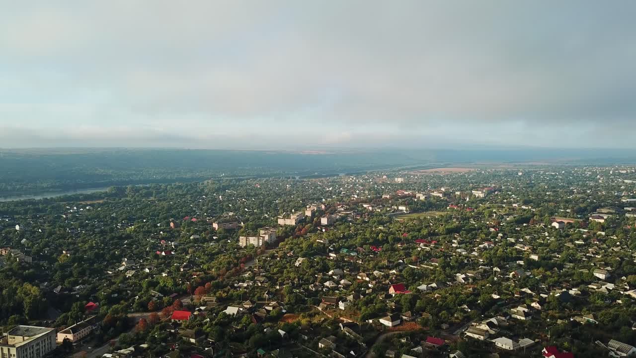Unbelievable view of a big town nearthe river and green trees in the morning. Aerial filming of beautiful landscape in summer. Motion from the bottom to top