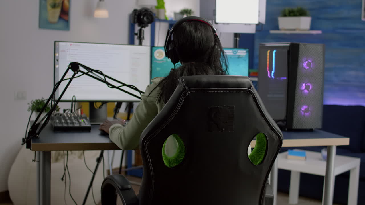 Back shot of streamer woman playing on powerful computer shooter game