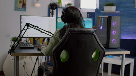 Back-shot-of-streamer-woman-playing-on-powerful-computer-shooter-game