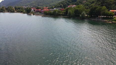 Calm-Waters-Of-Lake-Como-With-A-View-Of-Residential-Houses-And-Green-Vegetation-In-Italy---aerial-drone-shot