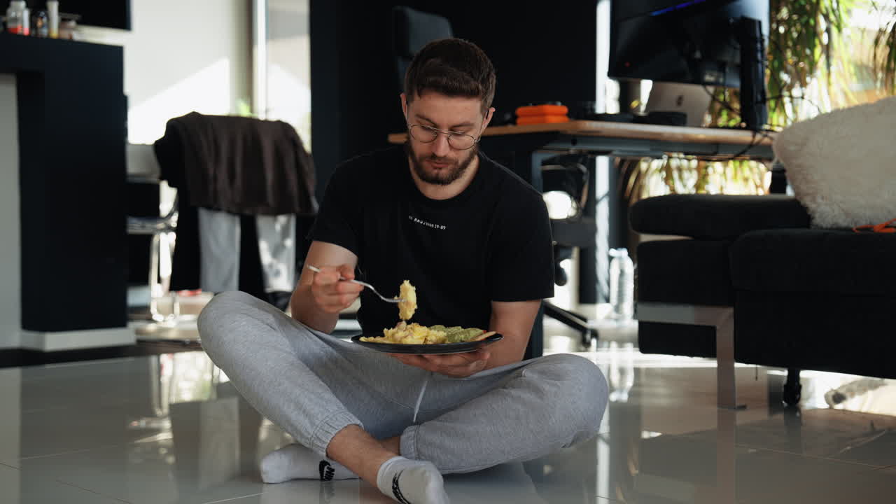 A relaxed man enjoying breakfast on the floor in a cozy home setting. Scrambled eggs, avocado, and calm vibes reflect slow mornings, mindfulness, and simple comfort at home