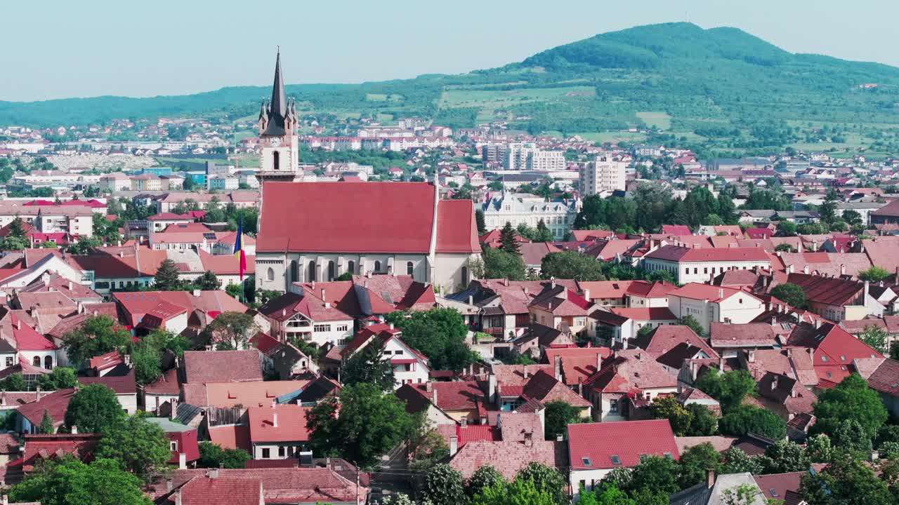 Et luftfoto fanger det historiske sentrumet av den europeiske byen, dominert av en stor kirke og dens spir. Boligområdet rundt, byen Bistrita, med den evangeliske kirken