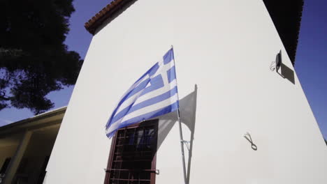 greek flag on a white wall waving in the wind - low-angle shot