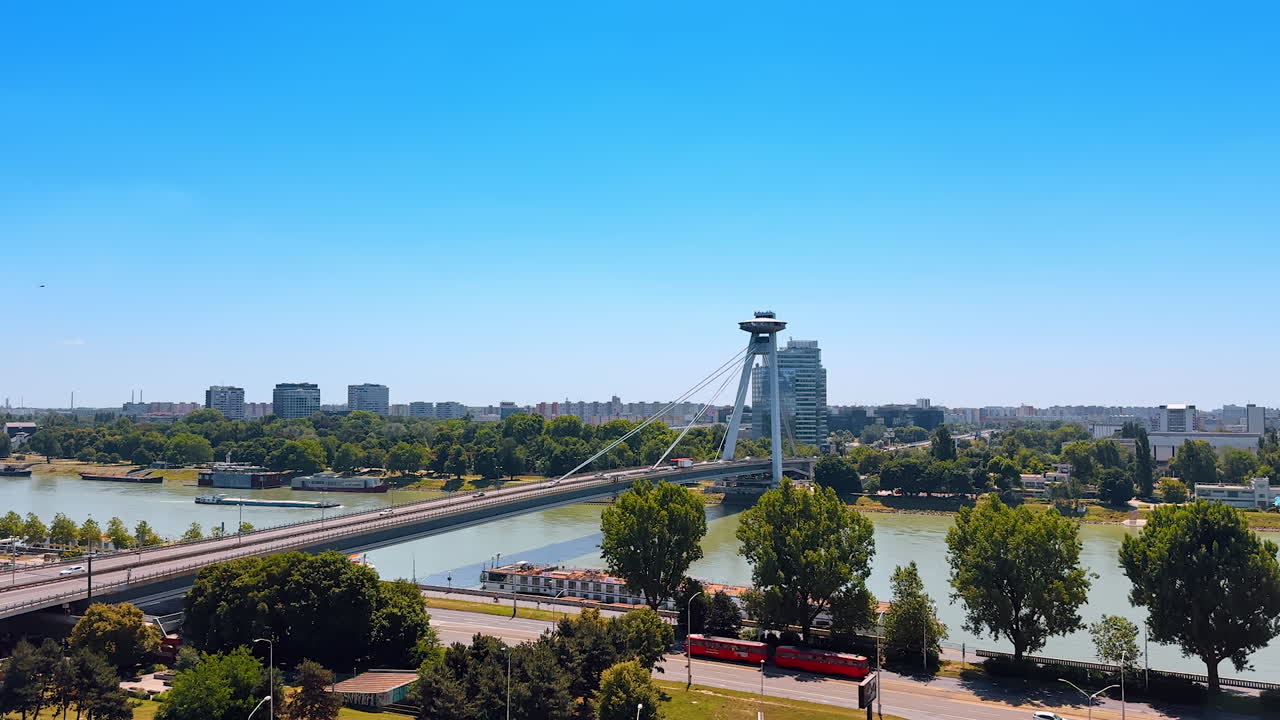 Waterfront of the Danube flowing in Bratislava, Slovakia. View on the UFO bridge crossed by many cars
