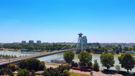 waterfront of the danube flowing in bratislava, slovakia. view on the ufo bridge crossed by many cars