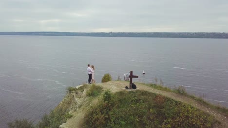 couple embracing on a cliff overlooking a river