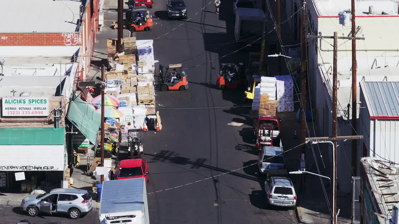 Overhead view of a busy commercial street with forklifts, pallets, and trucks