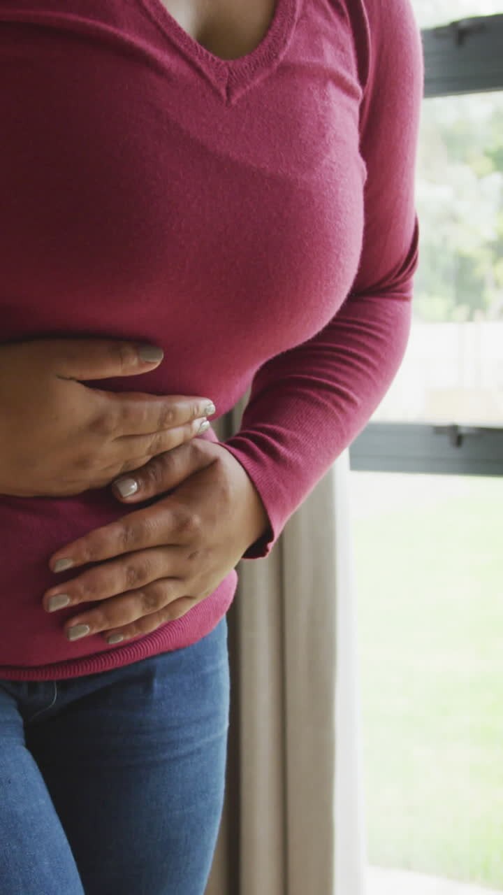 Video of midsection of plus size african american woman having stomach ache