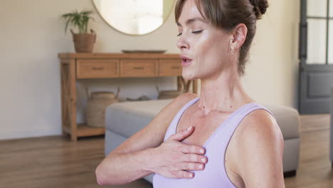 Middle-aged-Caucasian-woman-practices-yoga-at-home,-with-copy-space