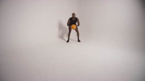 full length studio shot of male basketball player dribbling and bouncing ball against white background 4