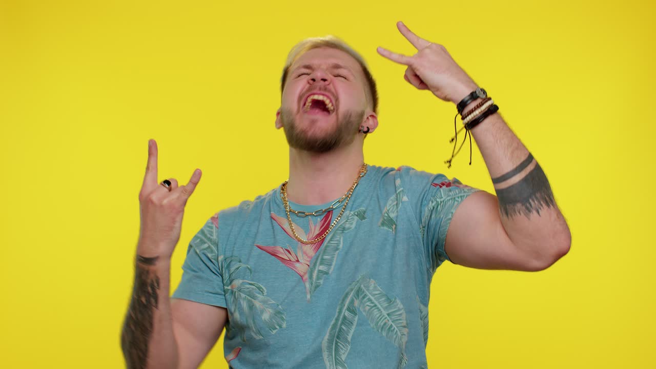 금발 머리카락, 문신과 선글라스를 입은 남자가 미소 짓고