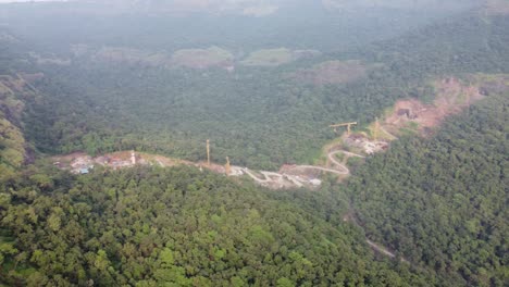 Luftaufnahme-Eines-Trümmerbergs-Oder-Eines-Schutthaufens-Mit-Muldenkippern,-Die-Mehr-Gesteinsschutt-Von-Einem-Tunnelbauprojekt-In-Einer-Hügeligen-Region-Entladen,-Was-Sich-Auf-Die-Lokale-Ökologie-Und-Das-Gelände-Auswirkt