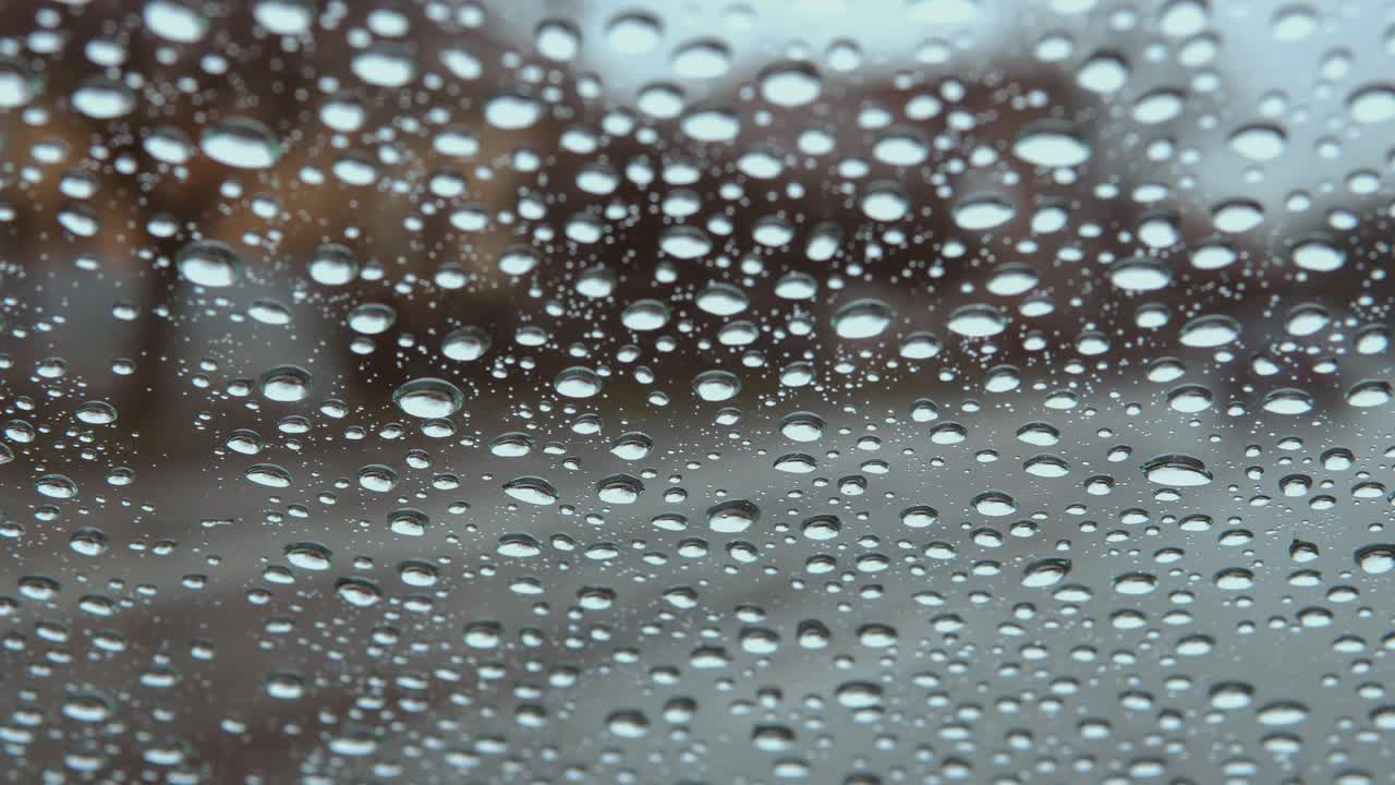 흐릿한 도시 자동차 조명 보케가 있는 자동차 창 유리에 빗방울이