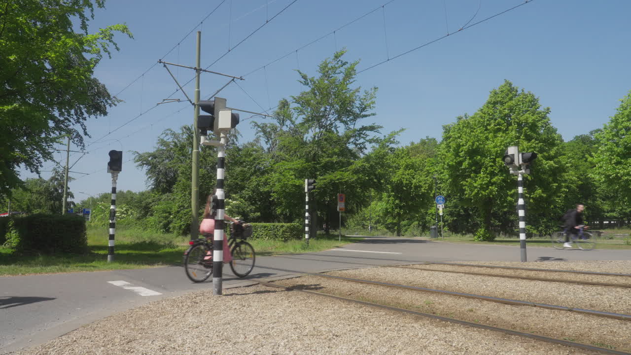 A tram passes a crossing close to the central of station of The Hague, Netherlands. After the tram passes, cyclists pass by.