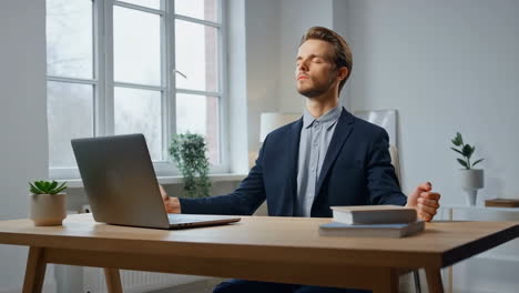 businessman meditating at desk in office