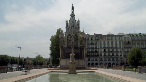 una piscina reflectante frente a edificios de estilo gótico en un parque en ginebra, suiza