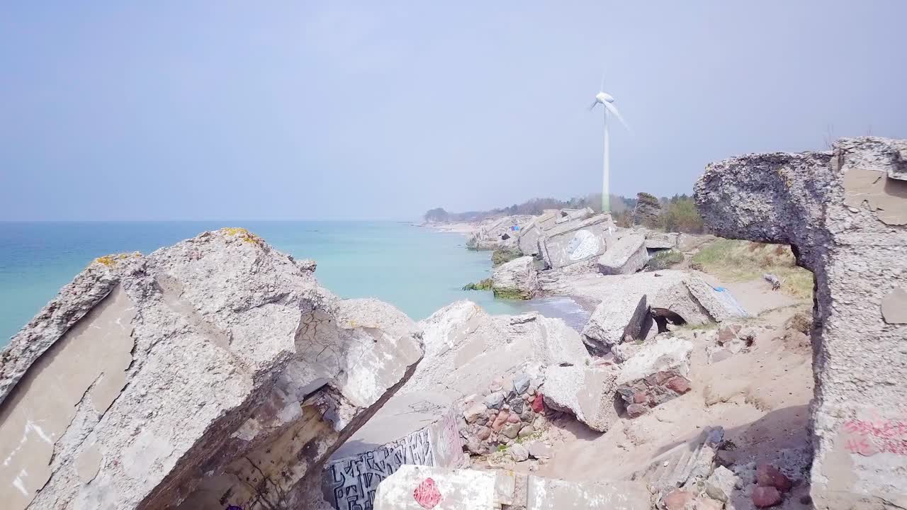 라트비아 리파야의 발트해 해변에 있는 카로스타 북부 요새에 있는 버려진 해변 요새 건물의 공중 전망, 화창한 날 잔잔한 바다, 광각 드론 샷이 앞으로 이동