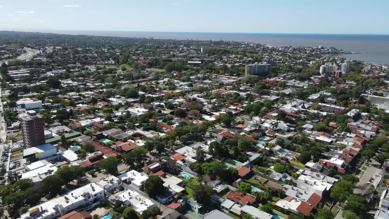 Urban development intersecting scenic coastline, revealing residential neighborhood along rio de la plata waterfront with architectural landscape spanning montevideo suburban areas