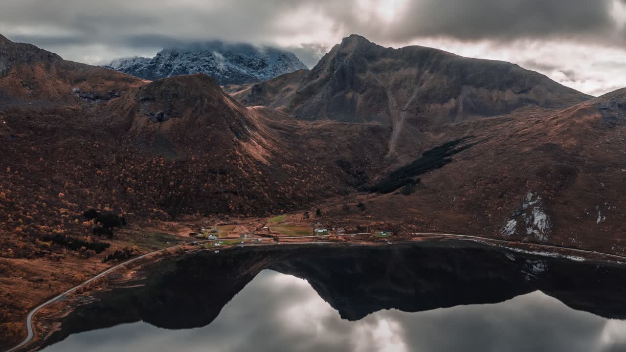 imponentes montañas y nubes grises reflejadas en las tranquilas aguas del fiordo como un espejo