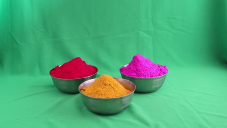 colorful holi | unidentified human hand setting bowls of coloured powder on a green screen | holi stock video for commercials and advertisement|