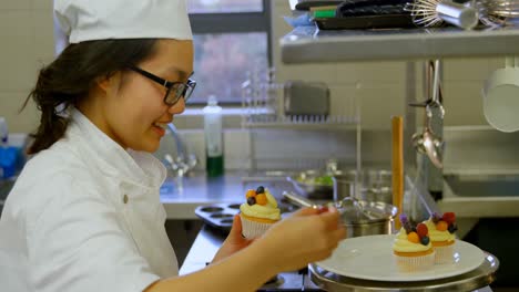 Female-chef-garnishing-muffins-in-kitchen-at-restaurant-4k
