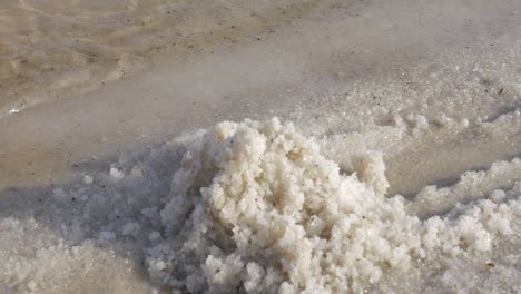 woman hands taking salt from the shore of dead sea