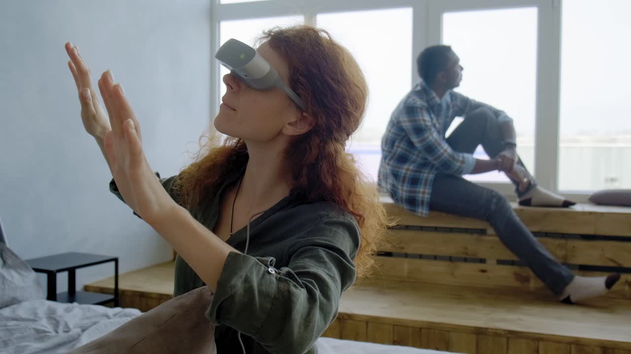 Woman using VR headset, man sitting by the window
