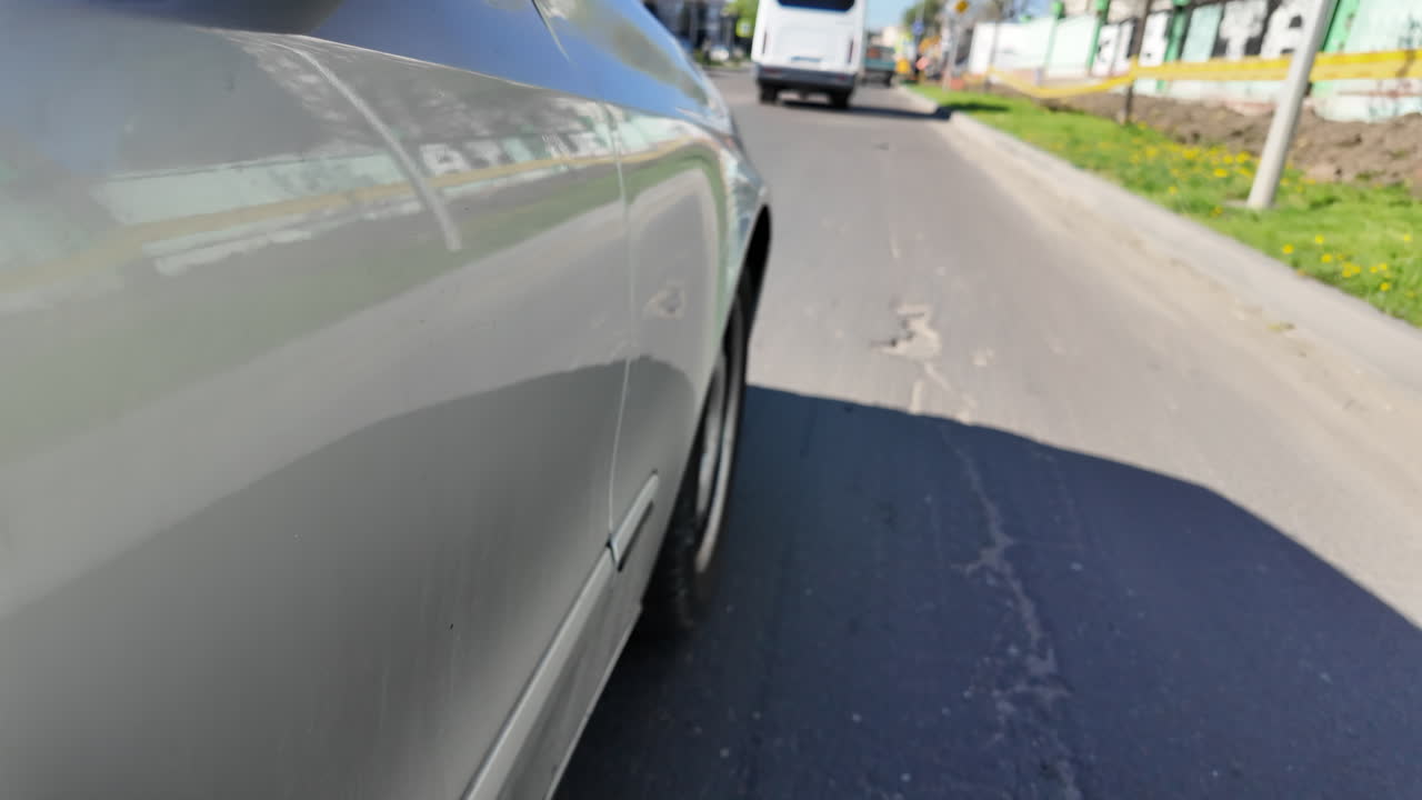 Close up of a silver car side driving down the road in city traffic