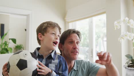 Glücklicher-Kaukasischer-Vater-Und-Sohn,-Die-Fernsehen-Und-Im-Wohnzimmer-Unterstützen