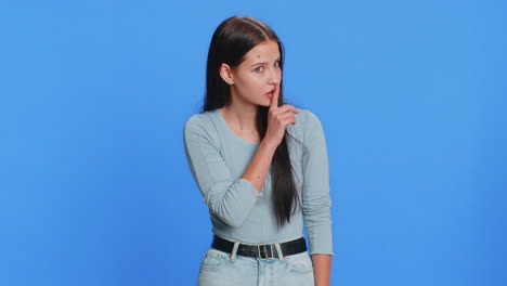 young woman presses finger to lips makes silence gesture sign do not tells secret stop gossip