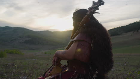 calm man in shaman clothes sits leaning on ikili in valley