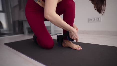 unrecognizable girl put on sports weights for the legs for training at home