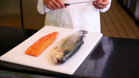 chef mostrando tabla de salmón entero y filete