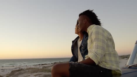 Couple-sitting-together-on-bonnet-of-pickup-truck-at-beach-4k