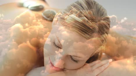 beautiful blonde women lying at spa with hot basalt stone on the back and cloudscape for valentine d