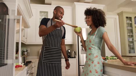 Glückliches-Gemischtrassiges-Paar,-Das-In-Seiner-Küche-Kocht-Und-Tanzt