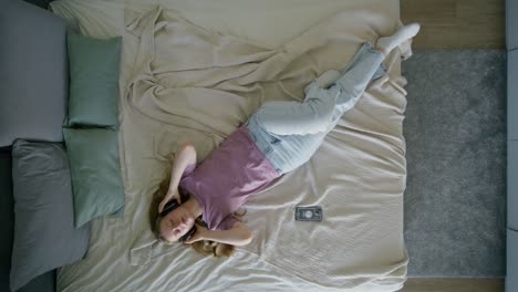 woman relaxing on bed with headphones