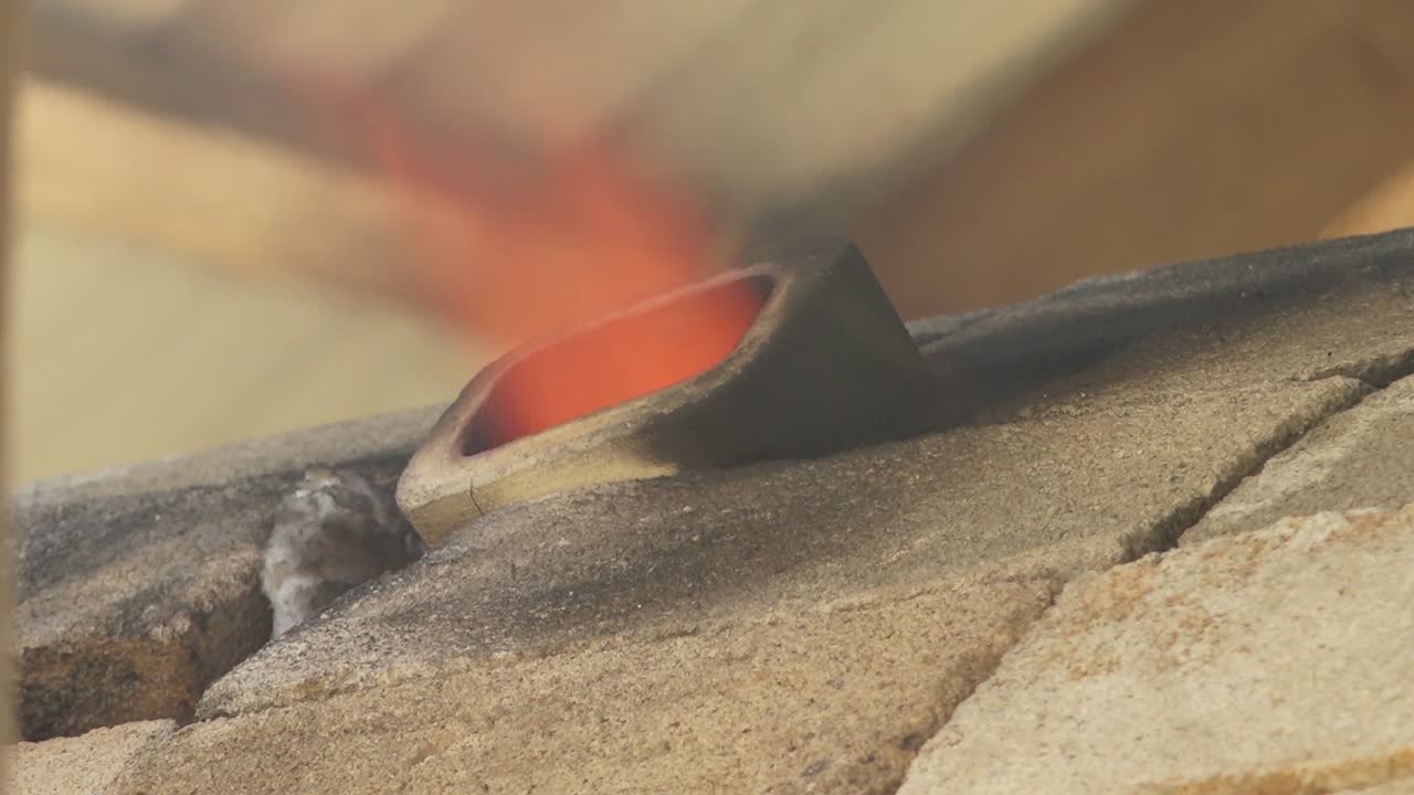 una llama grande e intensa es visible ardiendo dentro de un horno, vista a través de una fenda estrecha