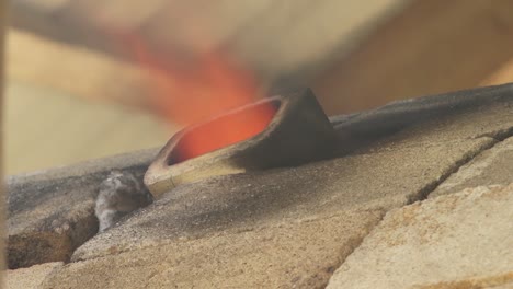 a large, intense flame is visible burning within a furnace, seen through a narrow slit