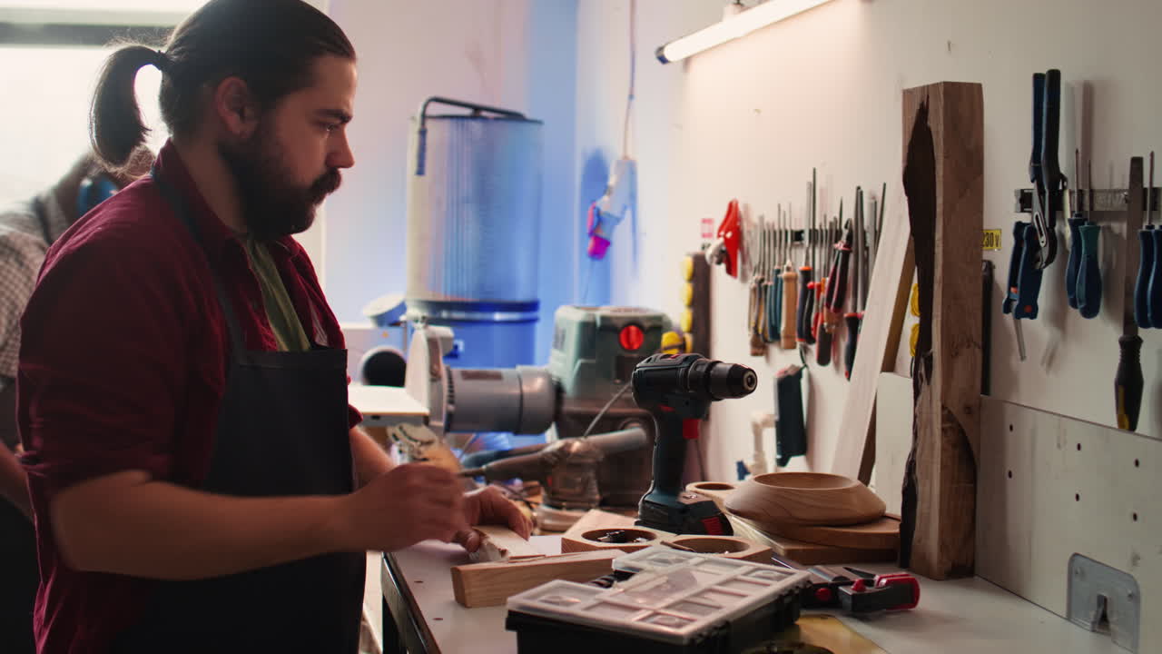 плотница меняет головку электробура в мебельной мастерской