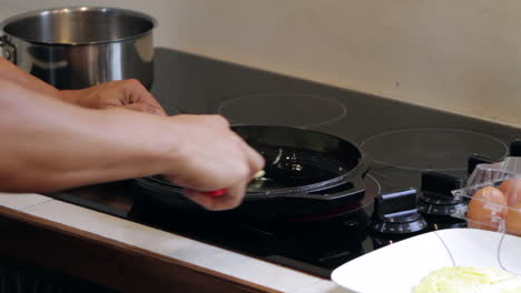 man cooks and flips egg in cast iron skillet