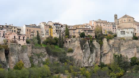 an overcast winter sky hangs above the famous hanging houses (casas colgadas) of cuenca, spain, creating a dramatic and moody scene of this historic city.