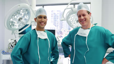 portrait of male surgeons standing with hands on hips in operation room