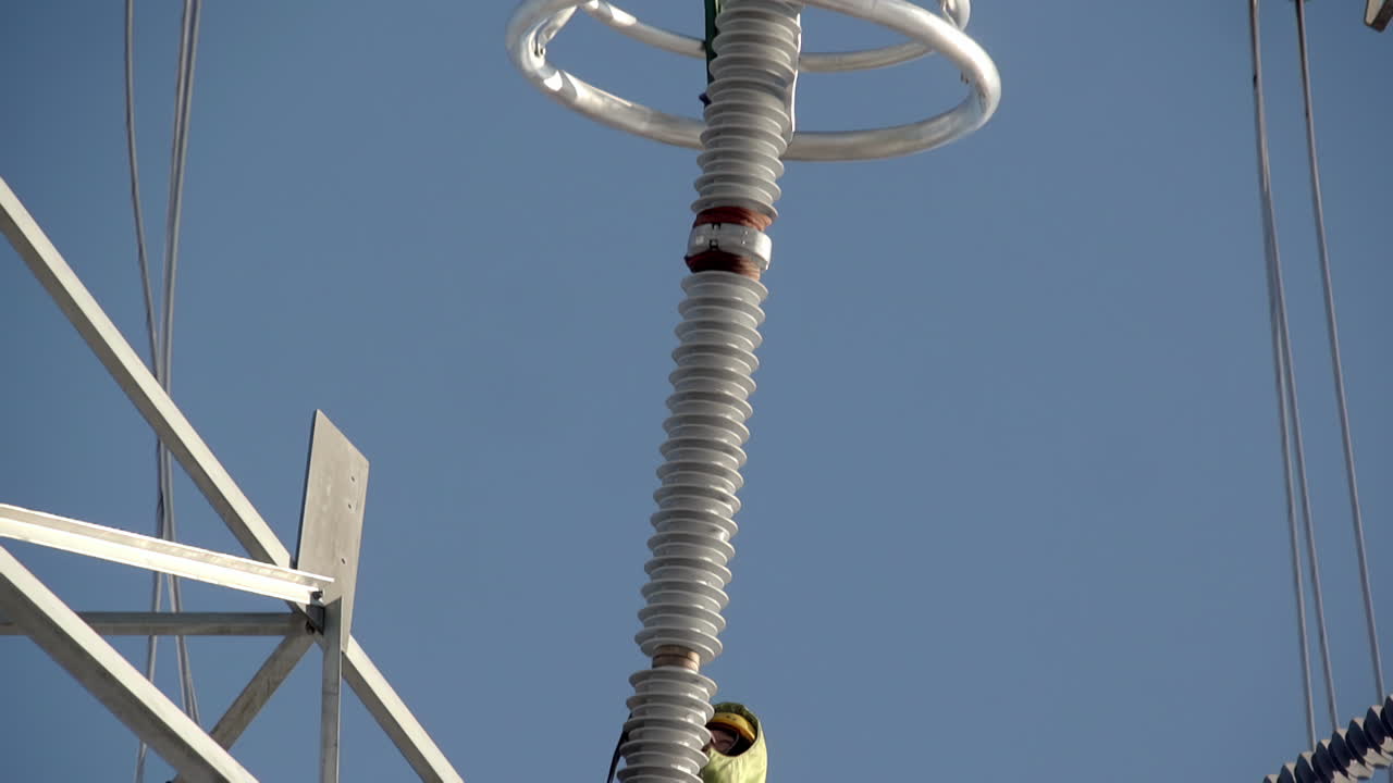 전송 타워의 단열 줄에서 일하는 라인맨의 기울기 아래 드러내는