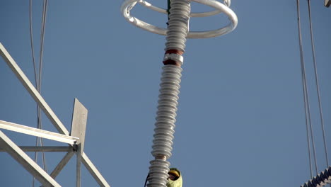 tilt-down reveal of linemen working on insulation string of transmission tower