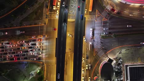 Topdown-View-Of-Cars-Driving-Across-Intersection-Roads-At-Night-In-Santo-Domingo,-Dominican-Republic