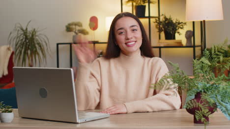 caucasian woman smiling friendly at camera waving hands gesturing hello hi greeting at home on sofa