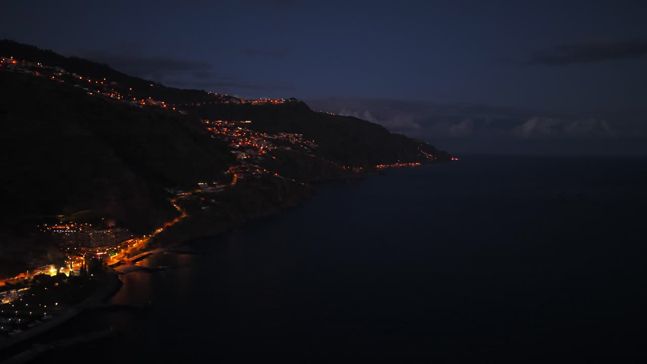 Illuminated Madeira coastline at night captured from an aerial view over Calheta. push forward