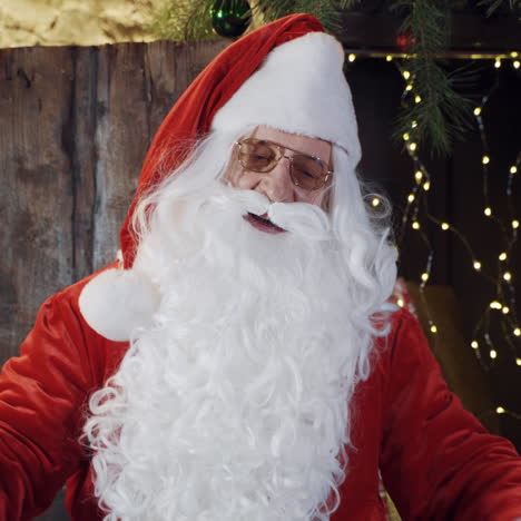 santa claus with long white beard is singing. santa wearing red costume and white gloves smoothing his beard on christmas background.