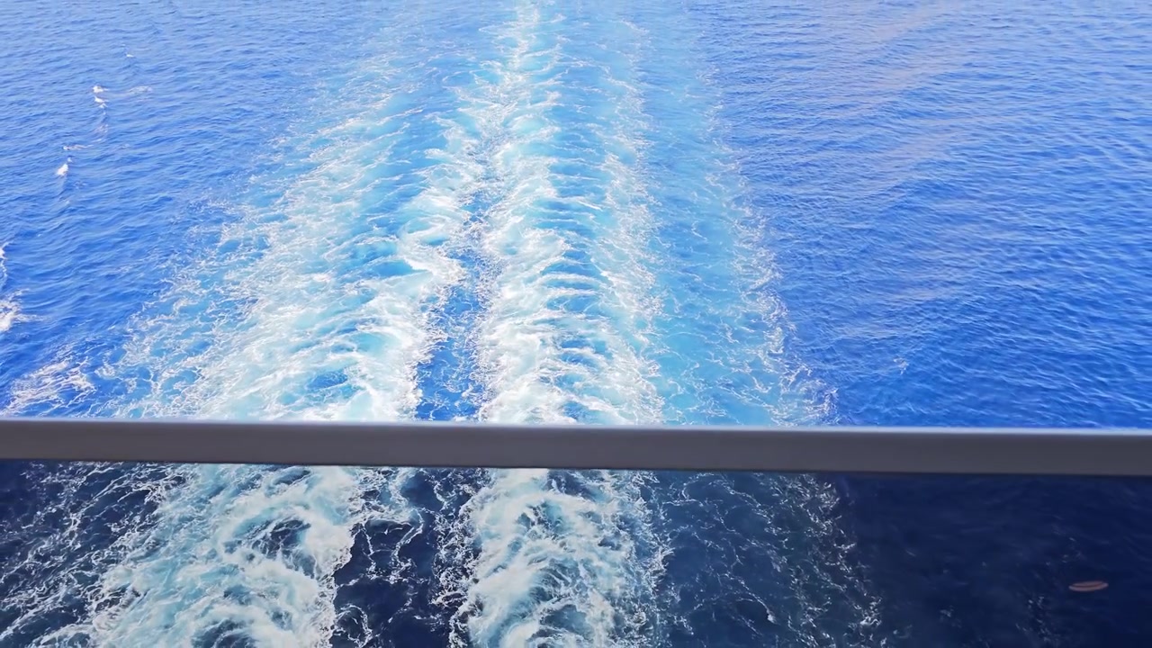 Solbelyste kølvandsspor bag et krydstogtskib, mens kameraet vipper op mod agterstavnen